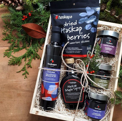 Haskapa gift crate tied with a bow and surrounded by Christmas tree branches and pinecones